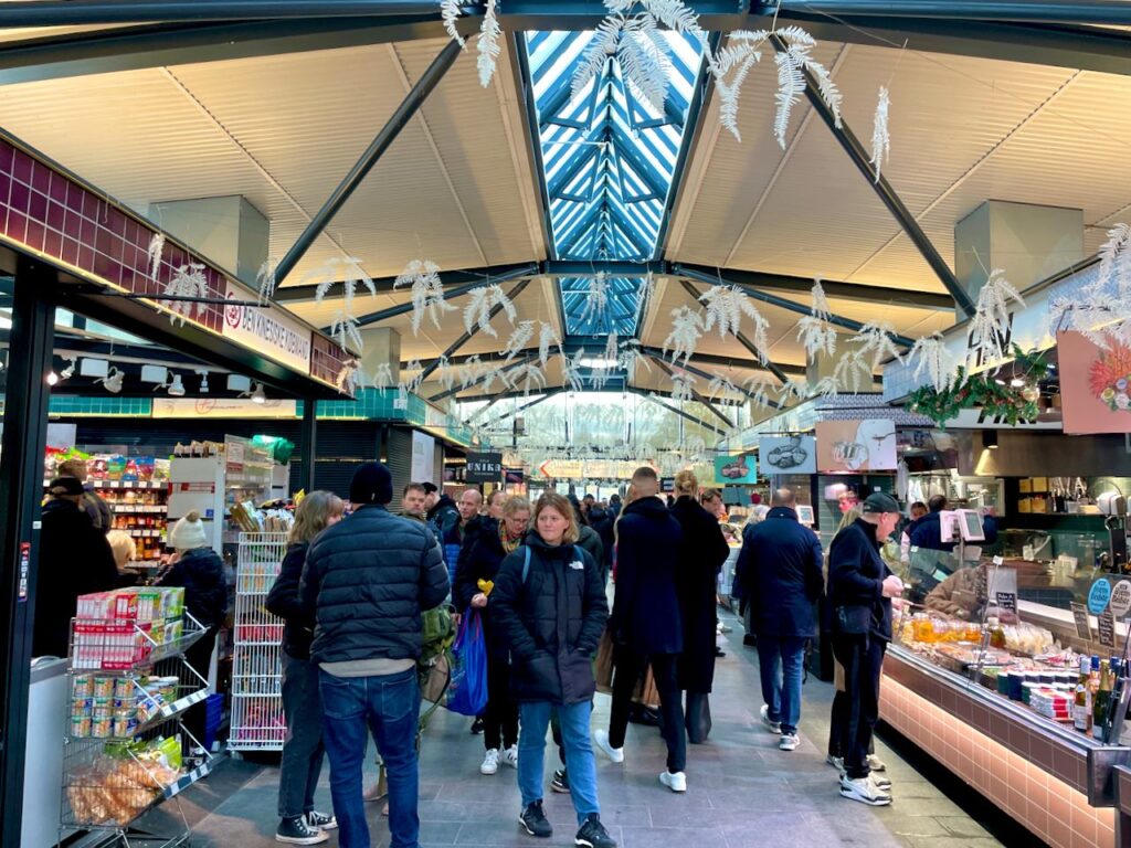 Torvehallerne food market in Copenhagen where people are strolling the food stalls
